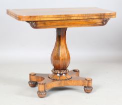 An early Victorian rosewood fold-over card table, the frieze with applied carvings, on a baluster