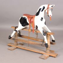 A 19th century carved and painted wooden rocking horse with later leather saddle and pine base,