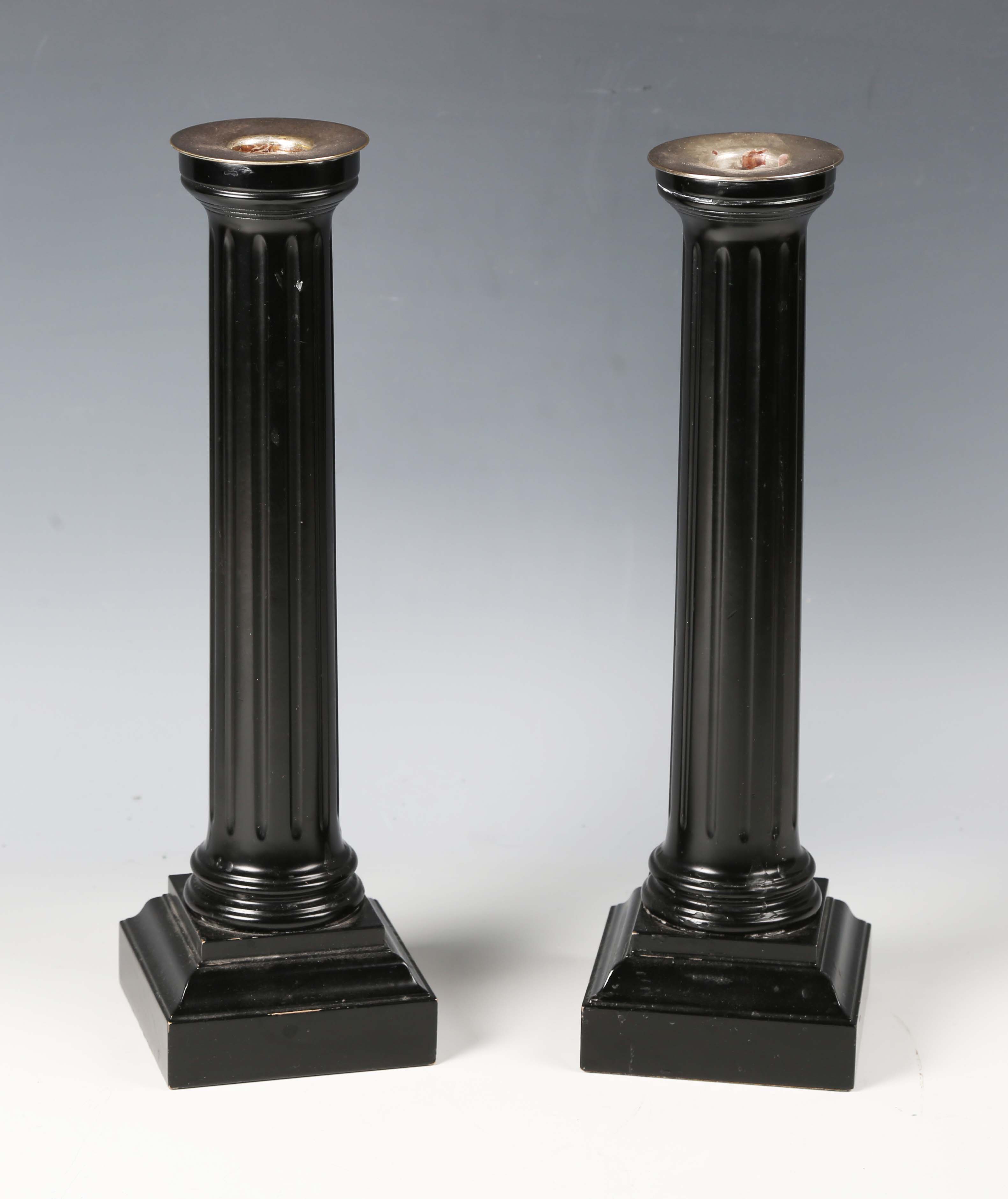 A pair of David Linley ebonized candlesticks with plated brass sconces and fluted columns,