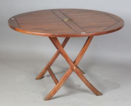 A modern teak folding circular garden table with brass fittings, height 75cm, diameter 120cm.Buyer’s