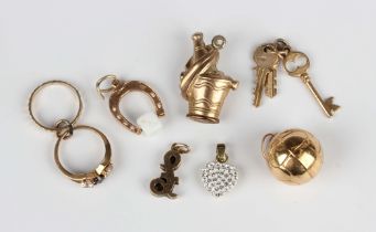 Six 9ct gold pendants and charms, comprising a horseshoe and dice, a pound sign, a football, a bunch