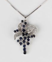 A white gold, sapphire and diamond pendant in a foliate spray and looped design, mounted with