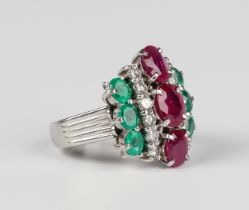 A platinum, treated ruby, emerald and diamond ring, claw set with three graduated oval cut treated