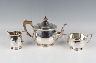 A George V silver three-piece tea set, each piece of circular form with foliate rim, on a stepped