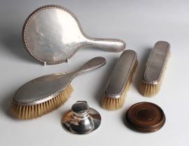 A George V silver four-piece dressing table set with egg and dart borders, comprising hand mirror,