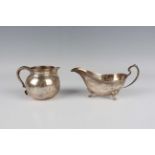 An Elizabeth II silver cream jug of circular squat form with scroll handle, reeded rim and beaded