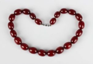 A single row necklace of graduated oval cherry coloured imitation amber beads, first half of the