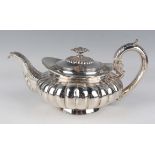 A George IV silver teapot of reeded squat circular form with foliate capped handle and scroll spout,