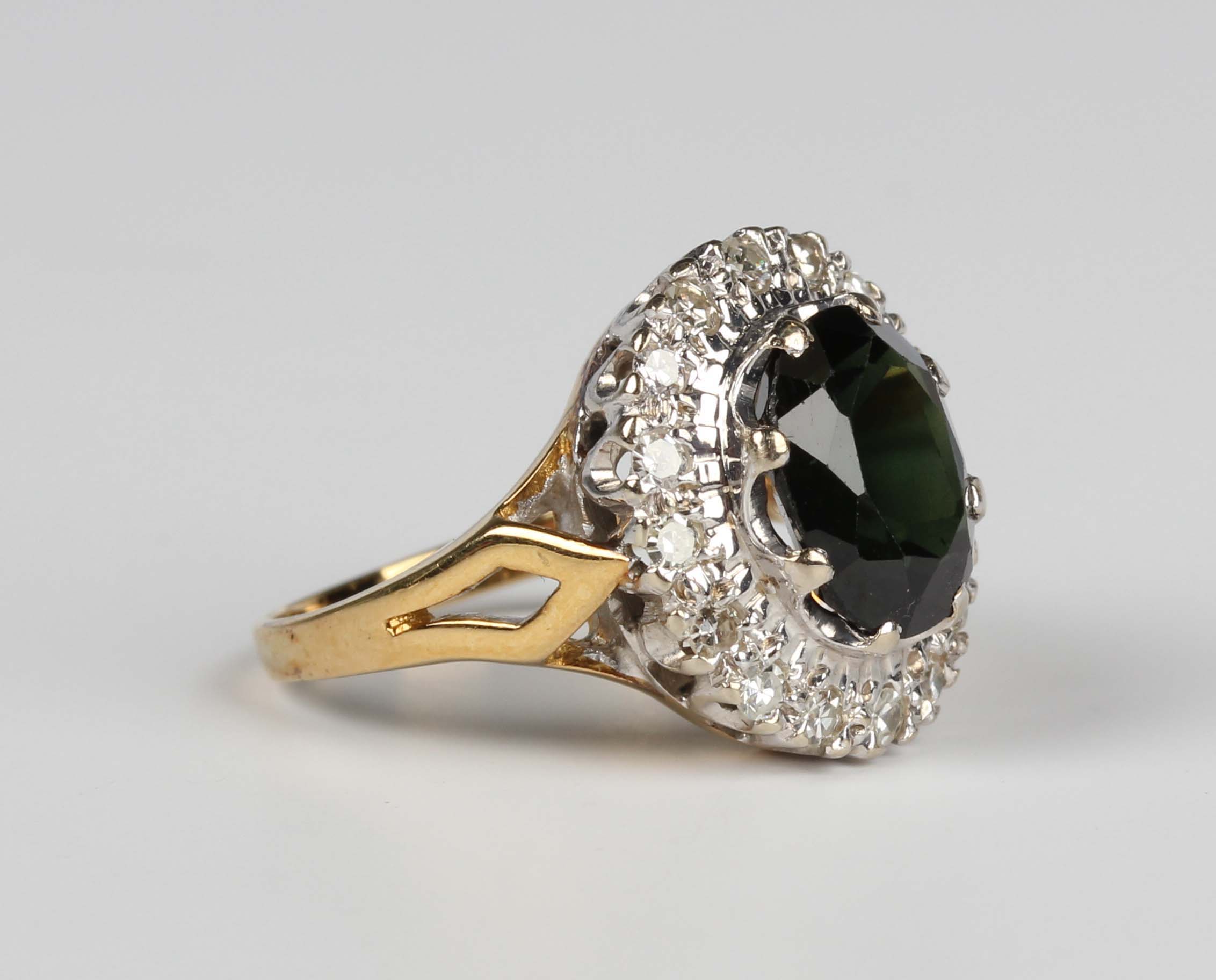 A gold, green sapphire and diamond oval cluster ring, claw set with the oval cut green sapphire