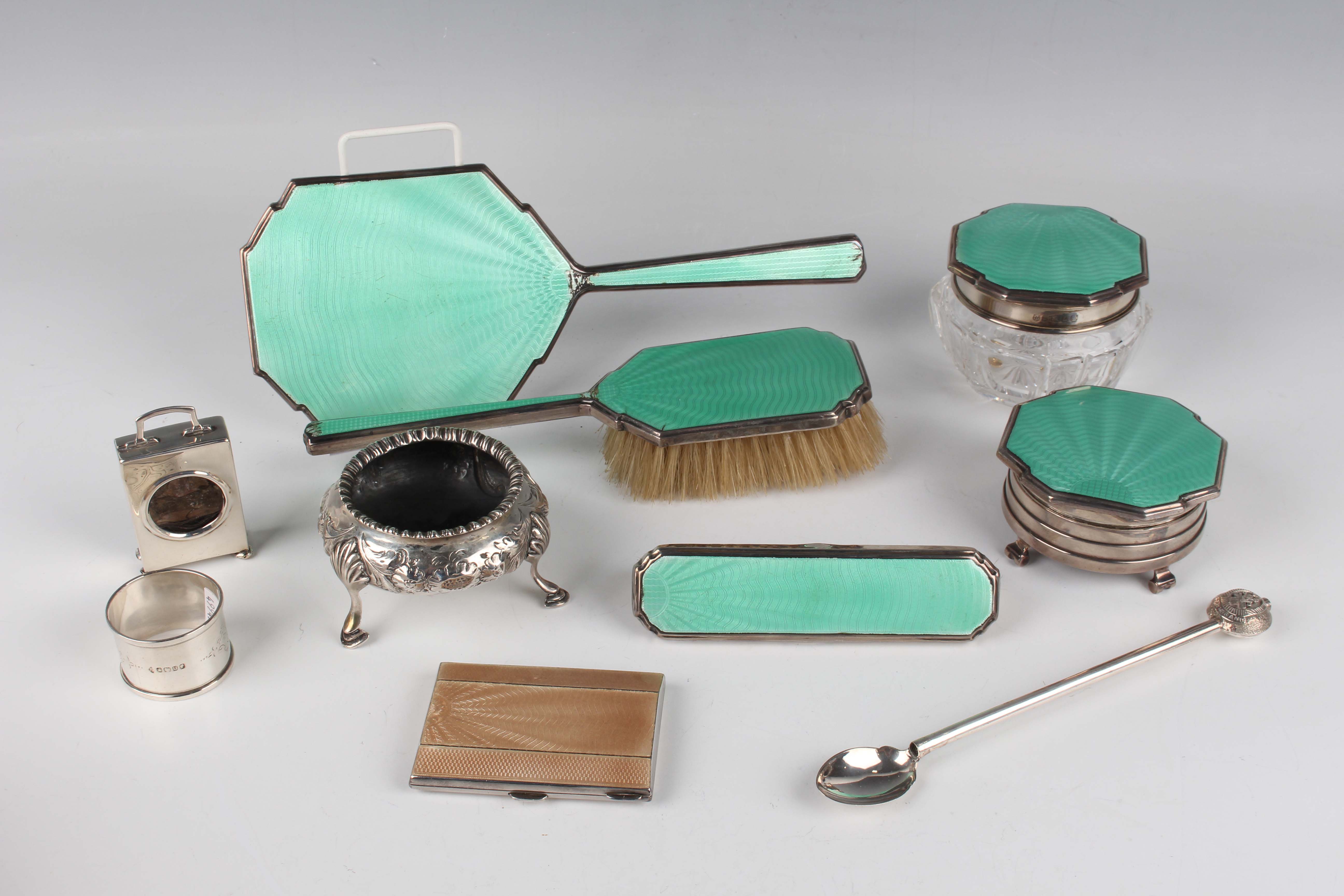 A George V silver and turquoise enamel four-piece dressing table set, comprising hand mirror,