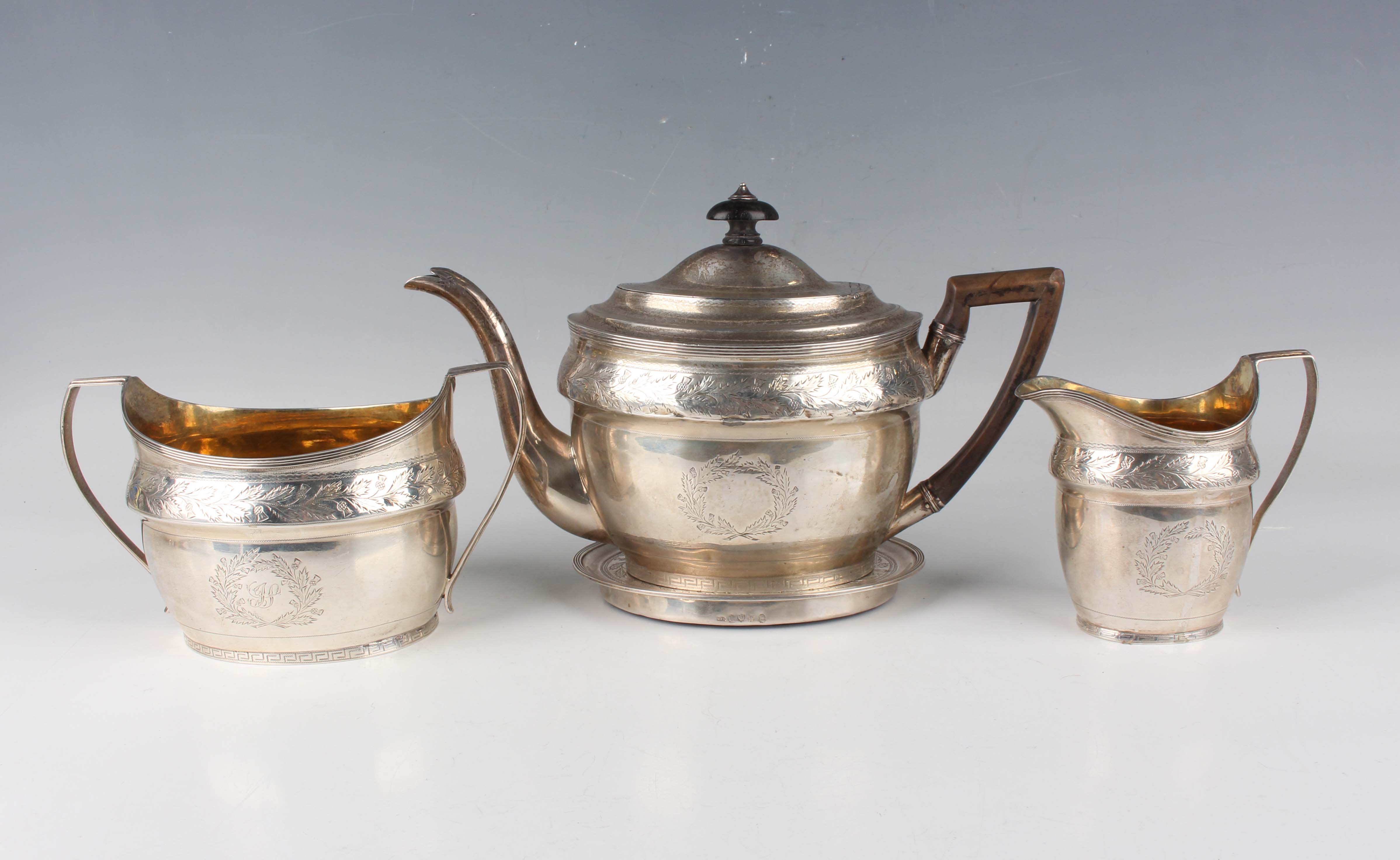 A George III Scottish silver four-piece tea set of oval form, engraved with a band of thistles above