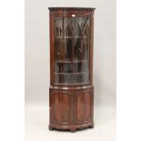 A mid-20th century reproduction mahogany bowfront corner cabinet with two lancet glazed doors,