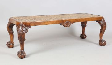 An early 20th century Queen Anne style walnut stool, the caned top on carved shell legs with claw