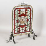 A Victorian and later stained and leaded glass firescreen, the panel painted with a central