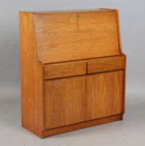 A mid-20th century teak writing cabinet by Remploy, the fall flap above drawers and cupboards,