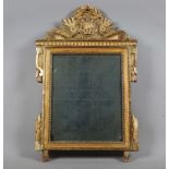 A late 18th century French giltwood wall mirror with laurel leaf and scroll surmount above a