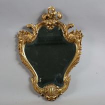 An early 20th century Rococo Revival gilded cast metal wall mirror of shaped cartouche form, 73cm