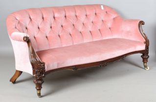 A good Victorian mahogany framed salon settee, upholstered in pink velour, the finely carved