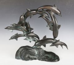 A late 20th century patinated bronze model group of dolphins, the integral base cast as waves,