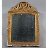 A late 18th century French gilt gesso wall mirror with foliate crest and distressed plate glass,