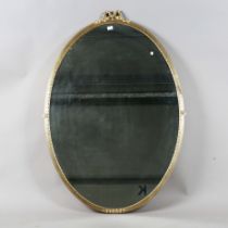 A large mid-20th century Neoclassical style gilt composition oval wall mirror with ribbon