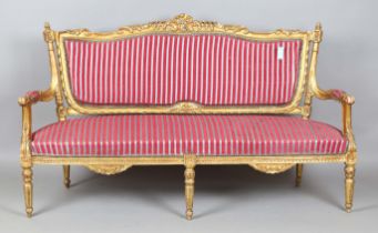 A 20th century Continental giltwood salon settee with a foliate carved frame and striped silk