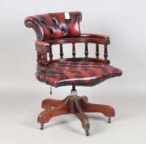 A late 20th century reproduction mahogany tub back revolving desk chair, upholstered in buttoned