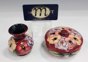 A Moorcroft circular box and cover and a matching vase in the Pansy pattern, dated 1993, designed by