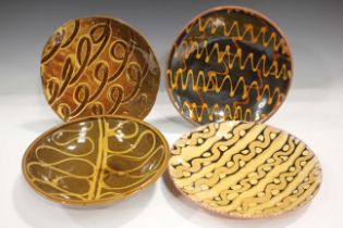 Four studio pottery slipware dishes, each of circular shape with a variety of squiggle and line