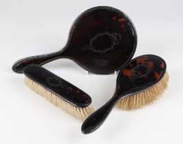 A George V silver and tortoiseshell three-piece dressing table set, comprising hand mirror,