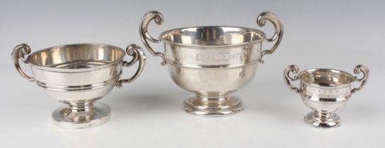 An Edwardian silver trophy cup of squat circular girdled form with flying scroll handles, the