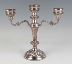 An Elizabeth II silver three-light twin-scroll branch candelabra, each circular sconce embossed with