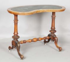 A Victorian walnut kidney shaped writing table, the top inset with green leather above a carved