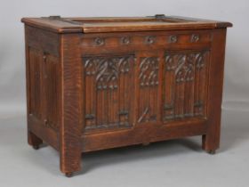 An early/mid-20th century Gothic Revival panelled oak coffer, the hinged lid above finely carved