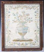 A George III silkwork panel, finely worked in coloured silks with a flower-charged urn within a