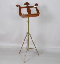 An early 20th century brass and mahogany adjustable music stand, the lyre top above a tripod base,