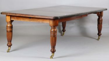 An Edwardian stained walnut extending dining table, the top with two extra leaves, raised on