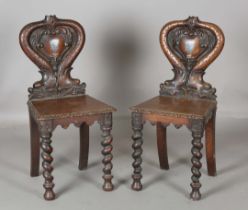 A pair of Victorian oak hall chairs, the shaped backs carved with opposing dolphins enclosing a