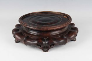 A Chinese hardwood circular stand, late Qing dynasty, the turned circular top above a carved and