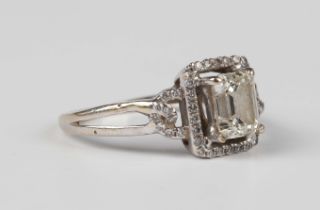 A white gold and diamond ring, claw set with the cut cornered rectangular step cut diamond within