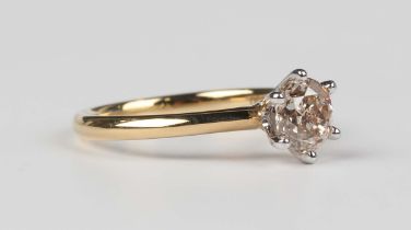 An 18ct two colour gold and diamond single stone ring, claw set with a circular cut diamond,