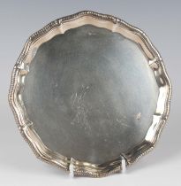A late Victorian silver circular card salver with piecrust and gadrooned rim, raised on claw and