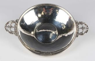 A George V silver circular shallow dish with hammered decoration, flanked by two cast and pierced