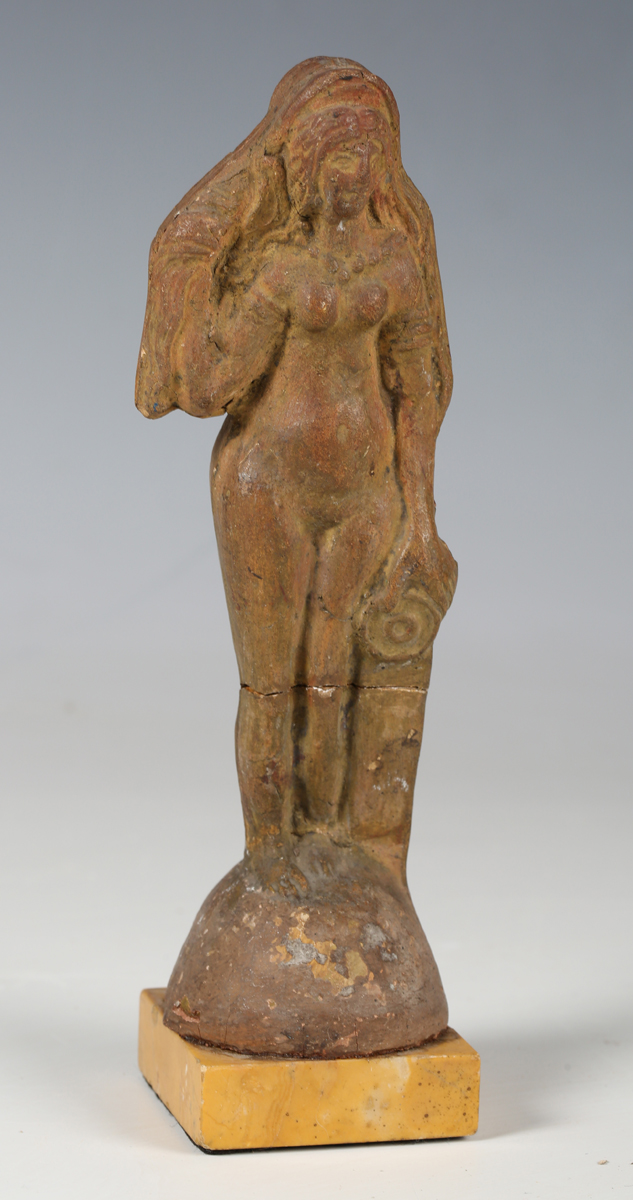 An ancient Roman terracotta full-length figure of a lady with long flowing hair, standing beside a