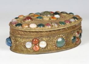 An early 20th century American gilt metal oval box and cover, inset with overall hardstone cabochons