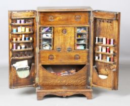 An early 20th century oak sewing cabinet, the two doors enclosing a fitted interior, containing