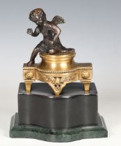 A 20th century cast bronze and brass figure of a seated cherub, raised on a green hardstone base,