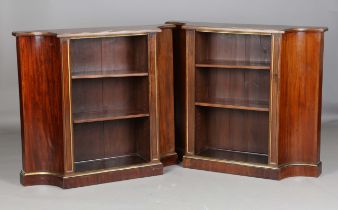 A pair of early 20th century Empire style mahogany open bookcases with gilt line borders and concave