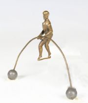 A 19th century patinated brass balancing acrobat model, holding a weighted wire, width 14cm.Buyer’