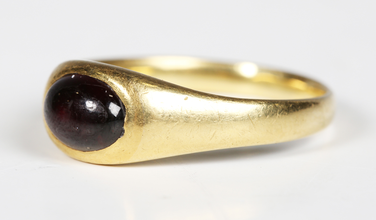 A medieval gold and garnet cabochon set ring, the garnet probably a later replacement, diameter 2cm.